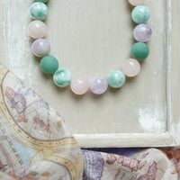 Multicolored beaded necklace on a textured surface with a map in the background