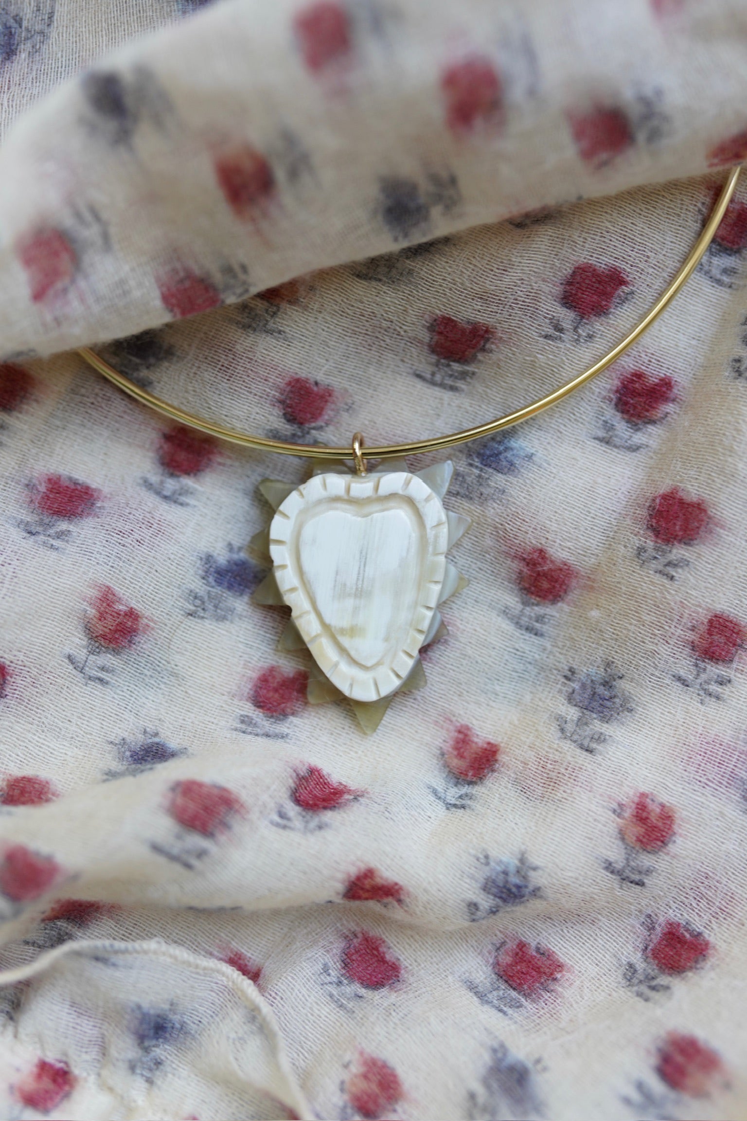 Necklace with a heart-shaped pendant on a floral fabric background