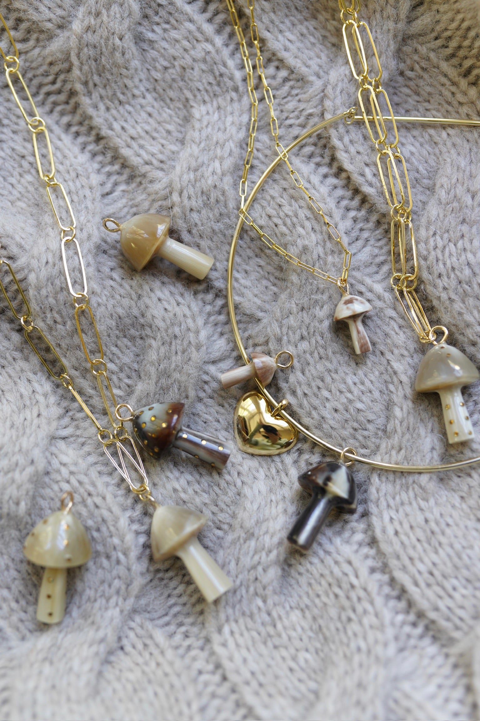 Gold necklaces with mushroom pendants on a textured fabric background