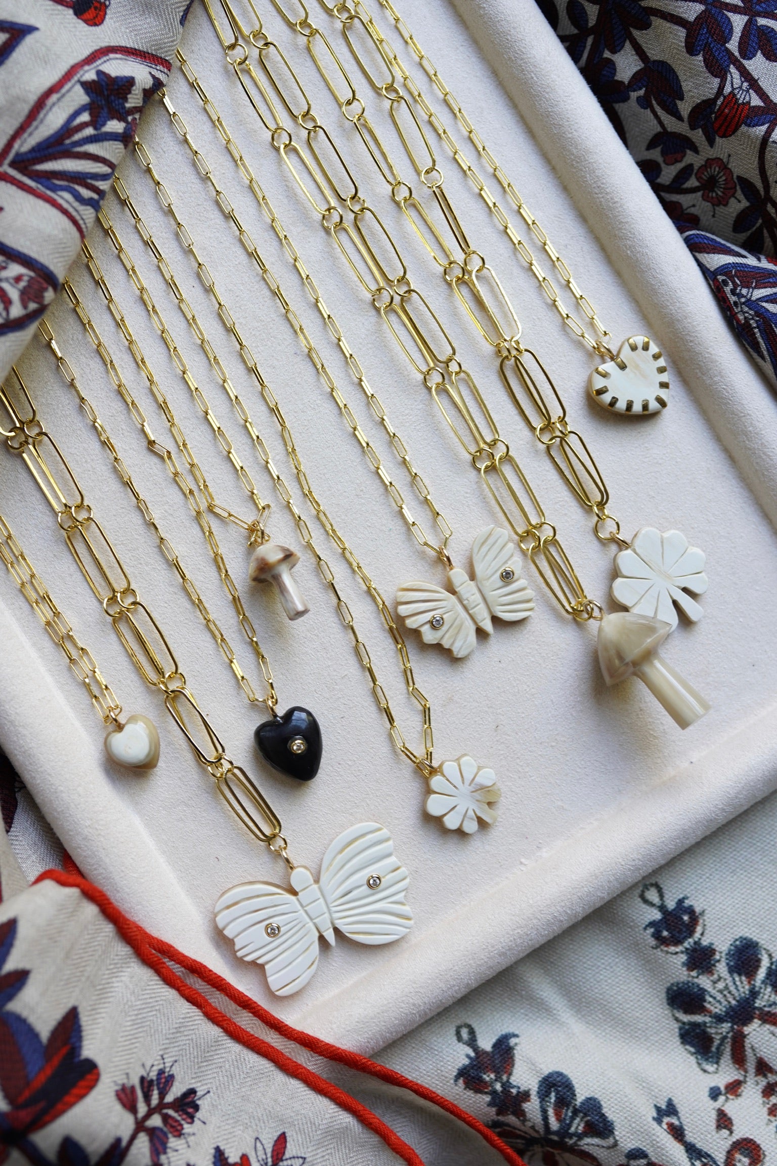 Gold necklaces with various pendants on a decorative surface