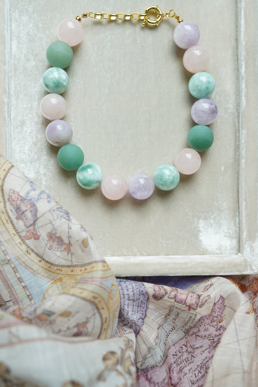 Multicolored beaded necklace on a textured surface with a map in the background