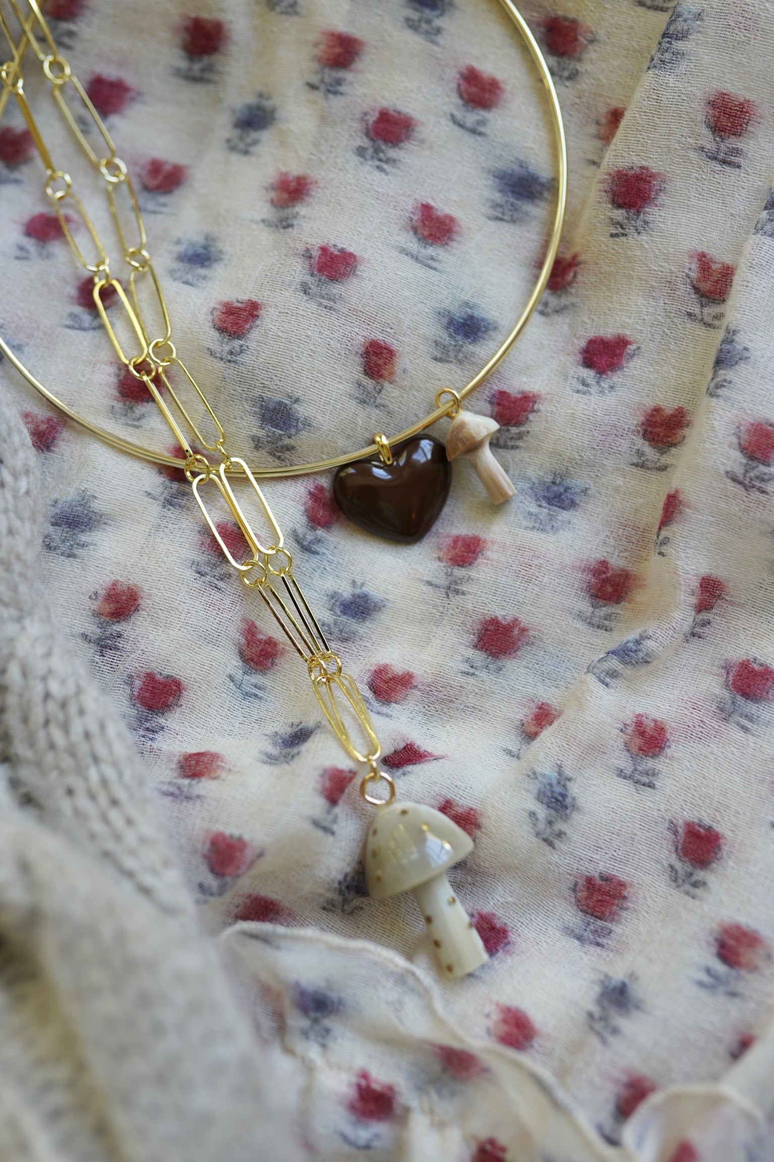 Gold necklace with heart-shaped pendant on floral fabric