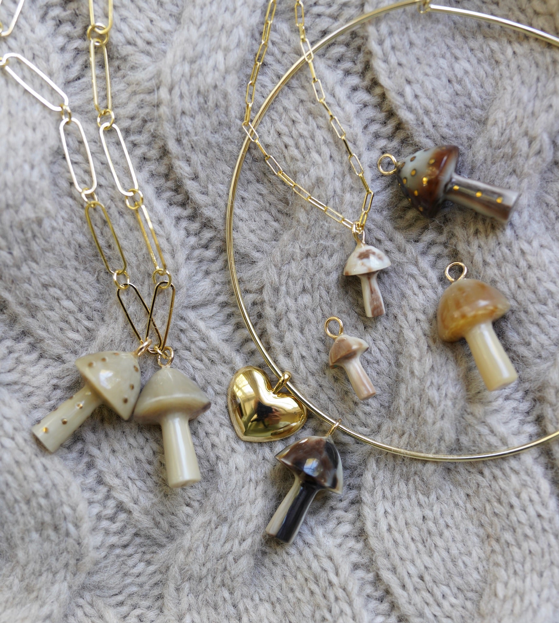 Gold necklaces with mushroom pendants on a textured fabric background