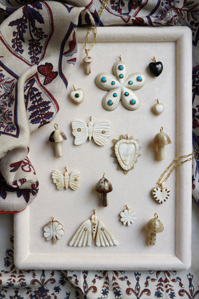 Collection of decorative earrings on a white tray with a patterned fabric background