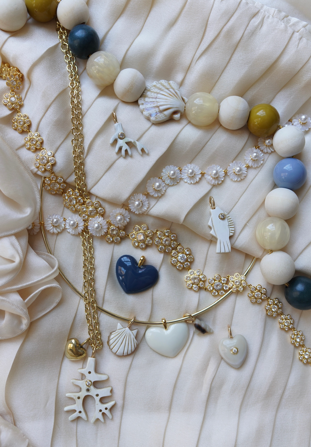 Necklace with heart and shell charms on a textured white surface