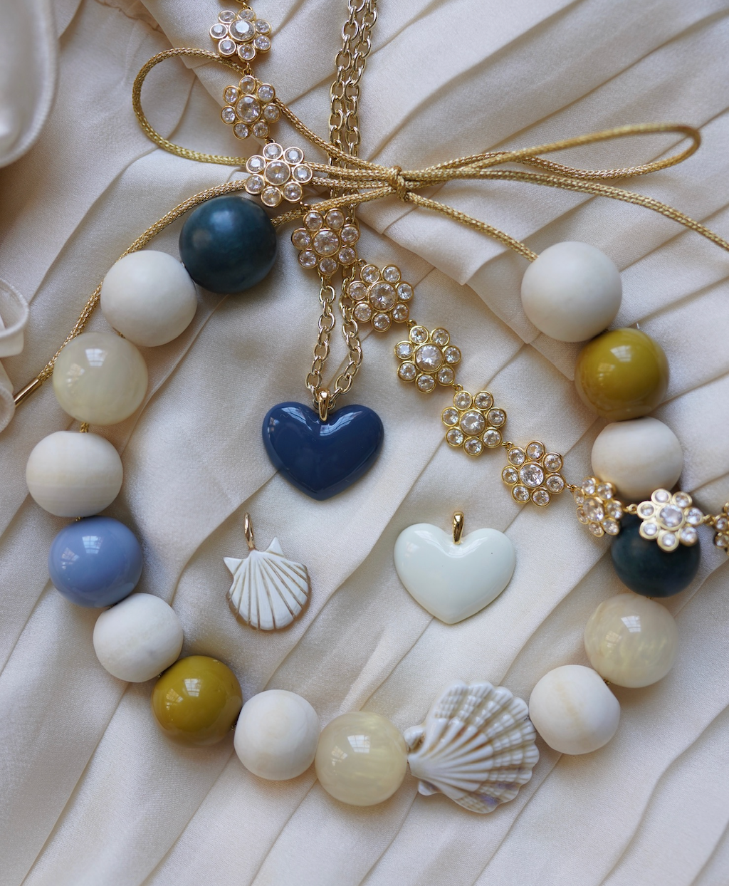 Necklace with heart-shaped blue pendant and shell charms on a textured white surface
